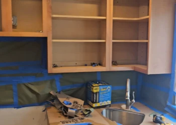 Preparation is the foundation of every successful cabinet painting project. These Burlington, Massachusetts cabinets have been carefully masked, protected, and disassembled in preparation for transformation using Benjamin Moore AF-70 Storm, a sophisticated gray that will give this kitchen a timeless, modern appearance. Unlike the rest, Finish Masters stands behind every project with our name, reputation, and written warranty. Finish Masters cabinet painting project in Burlington Massachusetts showing kitchen cabinets prepared and masked for painting in Benjamin Moore AF-70 Storm with surfaces protected before sanding and primer application.
