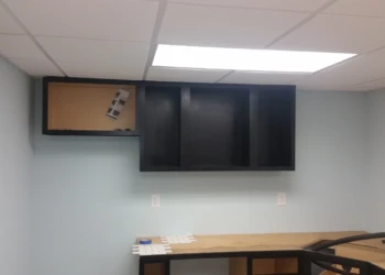 Black painted oak upper kitchen cabinets installed on a light blue wall in a basement kitchen in Billerica MA