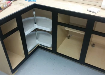 Base kitchen cabinets with black painted frames and natural wood interiors in a corner layout, showing two rotating shelves.