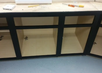 Matte black painted oak kitchen cabinets without doors showing inside shelving and workspace in Billerica basement