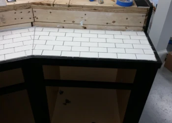 Corner bathroom vanity with black painted cabinetry base and white tiled countertop in Billerica MA basement