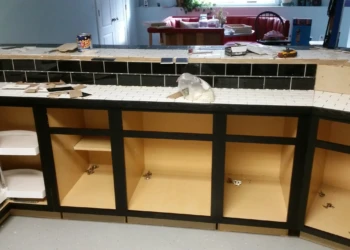 Base kitchen cabinets with black painted frames and natural wood interiors, without doors, in a basement kitchen in Billerica MA