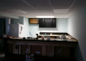 Basement kitchen area with newly installed black painted cabinets above a counter under construction