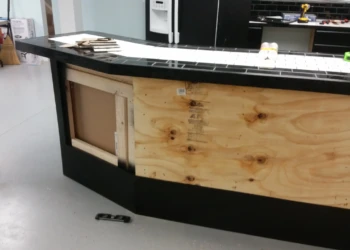Close-up of a basement kitchen island with black painted oak cabinetry and a tiled countertop in Billerica MA