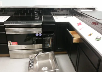 Black painted oak kitchen cabinets with white countertop and stainless steel appliances in a basement kitchen in Billerica MA