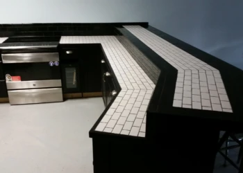 Black painted oak kitchen cabinets with a white subway tile countertop and stainless steel appliances in a Billerica MA kitchen