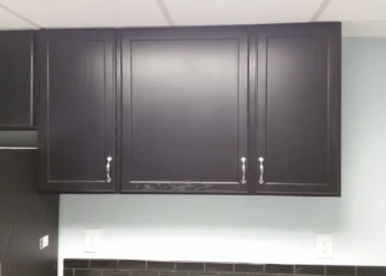 Close-up of matte black painted oak kitchen cabinets with silver handles above countertop in Billerica, MA kitchen