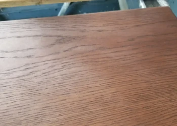 Close-up of a brown stained wooden cabinet panel with a smooth, high gloss finish