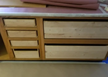 Unfinished wooden cabinetry base with drawers removed and preparation materials nearby during cabinet painting in Billerica MA