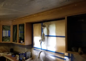 Brown wooden kitchen cabinets masked and taped for cabinet painting preparation in Billerica MA