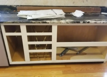 Off-white painted kitchen cabinet base without drawers and doors, showing open compartments and marble countertop above