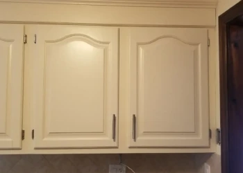 Close-up of off-white kitchen cabinet doors with classic panel design and metal handles in Billerica home.