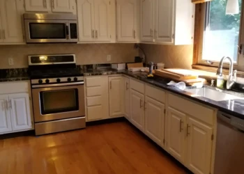 Kitchen with off-white painted cabinets, stainless steel appliances, dark granite countertops, and hardwood floor in Billerica MA