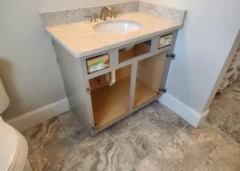 Open gray bathroom vanity cabinet with marble countertop and integrated sink in North Andover bathroom