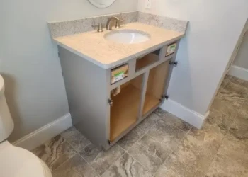 Bathroom vanity cabinet with light-colored countertop and open storage space in a bathroom corner