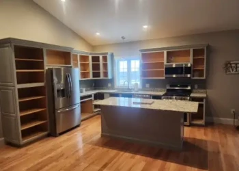Kitchen with cabinets mid-refinishing showing open cabinet shells and an island under renovation in North Andover MA