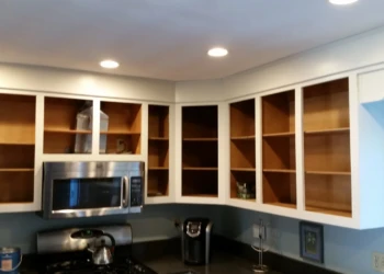 Open upper kitchen cabinets without doors above stainless steel microwave and stove in North Andover kitchen