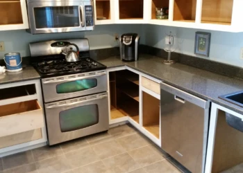 Partially disassembled kitchen cabinets with doors and drawers removed around a stainless steel stove and dishwasher in North Andover MA