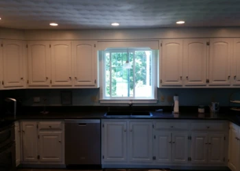 White painted kitchen cabinets surrounding a window above a black sink with stainless steel dishwasher in North Andover kitchen