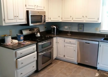 White painted kitchen cabinets with stainless steel stove, microwave, and dishwasher in North Andover kitchen
