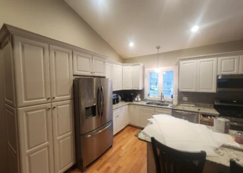 Light-colored refinished kitchen cabinets surrounding stainless steel fridge and stove with granite countertops in North Andover kitchen