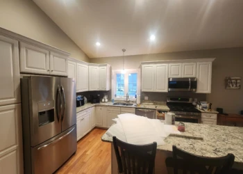 Bright kitchen with freshly painted white cabinets, granite countertops, stainless steel appliances, and hardwood floors
