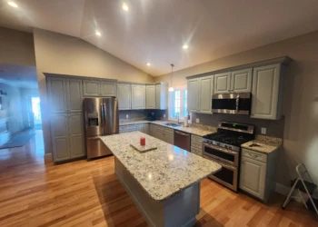 Kitchen with gray painted cabinets, granite countertops, stainless steel appliances, and wooden floor in North Andover MA