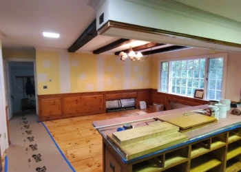 Kitchen with stripped cabinets and pine flooring showing preparation for cabinet painting in Bedford NH