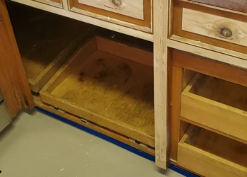 Close-up of natural unfinished wooden kitchen cabinets beneath a gas cooktop showing cabinet refinishing preparation in Bedford NH