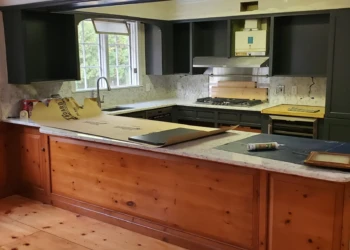 Kitchen cabinets with a dark paint finish around a white marble countertop in a Bedford, NH home undergoing cabinet painting