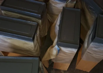 Several cabinet doors wrapped and painted dark gray in a workshop preparing for cabinet painting in Bedford NH