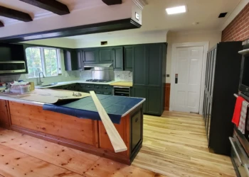Kitchen with dark green painted cabinets, pine flooring, and marble backsplash in Bedford NH kitchen cabinet painting project