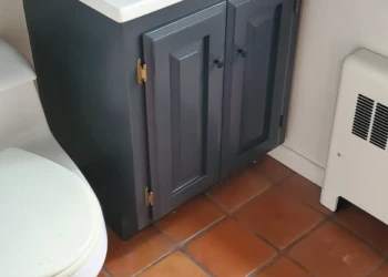Small bathroom vanity cabinet painted dark gray with white countertop and patterned sink basin in Bedford, NH bathroom