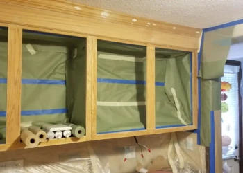 Wood cabinet frames masked with tape and covered to protect surfaces during refinishing in Billerica MA kitchen