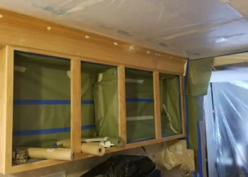 Wood kitchen cabinets masked and prepped for refinishing with protective coverings in Billerica MA