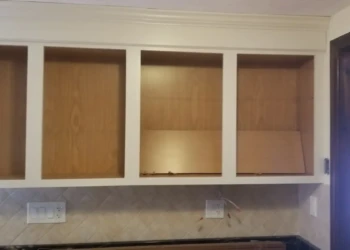 Kitchen cabinets with off-white painted frames and natural wood interiors, in a Billerica home