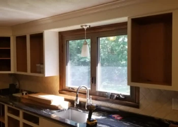 Open kitchen cabinets with natural wood interiors and white painted frames around a window and countertop in Billerica MA