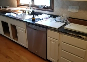 Section of kitchen cabinetry with some cabinet doors removed and others placed on countertop in Billerica kitchen.