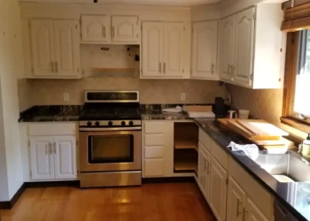 Off-white painted kitchen cabinets with metal handles in a Billerica MA kitchen during refinishing project by Finish Masters Builders Corp