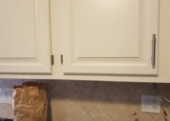 Close-up view of off-white painted kitchen cabinet doors with modern hardware and tiled backsplash in Billerica home