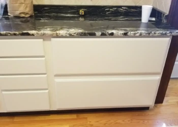 Refinished kitchen cabinets painted in light off-white color with black and white granite countertop in Billerica kitchen
