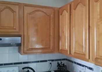 Close-up of brown stained kitchen cabinets with a high gloss finish above a stove and tiled backsplash