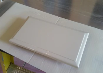Close-up of a refinished white kitchen cabinet door laid flat for drying or inspection
