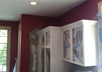 White kitchen cabinets being refinished with protective plastic coverings during painting process in Carlisle MA kitchen