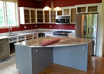 Kitchen with refinished cabinets and a gray island topped with marble in Carlisle, MA kitchen cabinet refinishing project