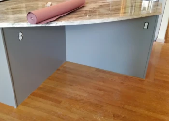 Close-up of kitchen island cabinets refinished in gray with marble countertop on hardwood floor in Carlisle kitchen
