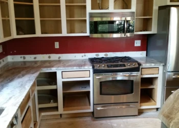 Kitchen showing kitchen cabinet refinishing in progress with open cabinet doors and newly installed marble countertops in Carlisle MA