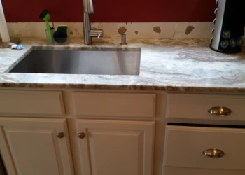 White refinished kitchen cabinets with silver handles and granite countertop with stainless steel sink in Carlisle MA kitchen