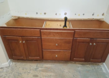 Wooden master bathroom vanity cabinets in Carlisle MA with drawers and doors, in early refinishing stage without countertop