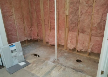Bathroom under remodel with exposed wall insulation and plumbing with no flooring installed in Carlisle MA